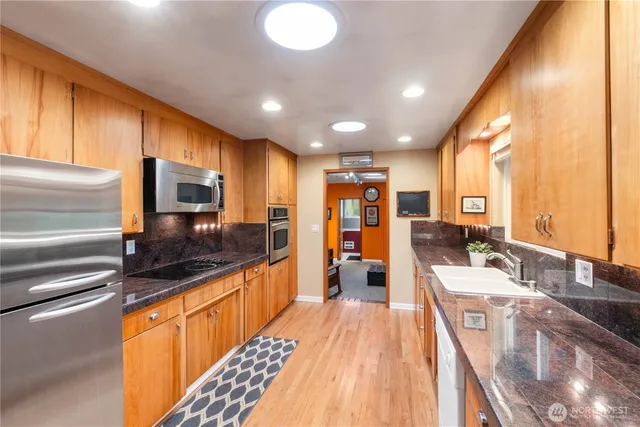 a large kitchen with stainless steel appliances a large counter top a stove and a sink
