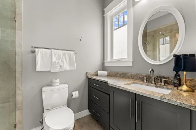 a bathroom with a granite countertop toilet sink and mirror