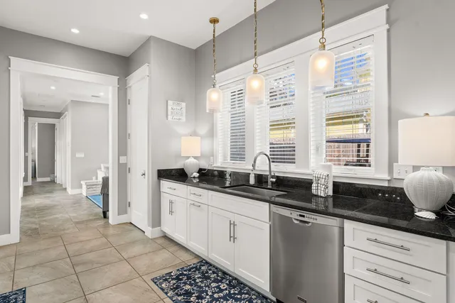 a kitchen with granite countertop a sink and a white cabinets