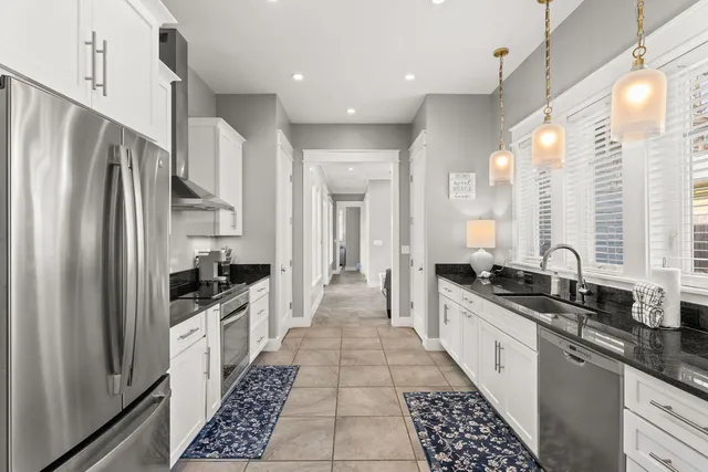 a large kitchen with stainless steel appliances a large counter top a stove a chimney a refrigerator and a stove