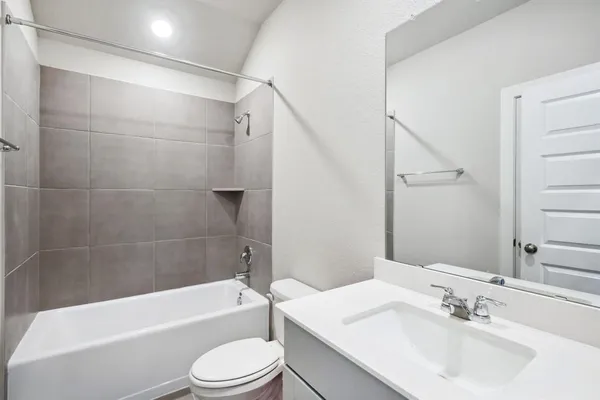 a bathroom with a bathtub shower sink vanity mirror and toilet