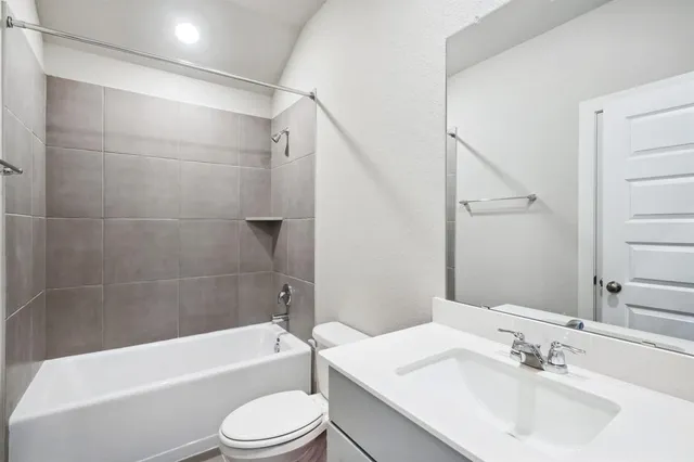 a bathroom with a bathtub shower sink vanity mirror and toilet