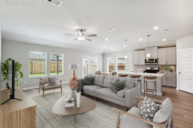 a living room with furniture kitchen view and a large window