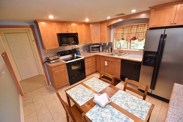55 Christopher Road Waltham, MA 02451 - Photo 5 of 19 a kitchen with granite countertop a refrigerator stove top oven dining table and chairs