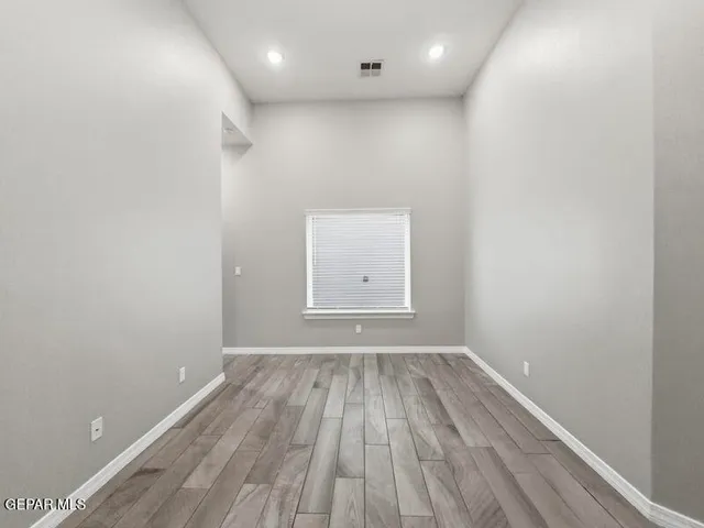a view of an empty room with wooden floor and a window