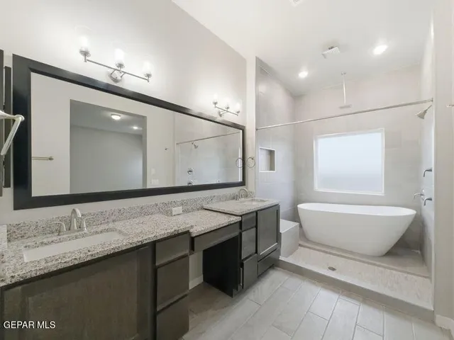 a bathroom with a granite countertop sink a toilet a mirror and bathtub