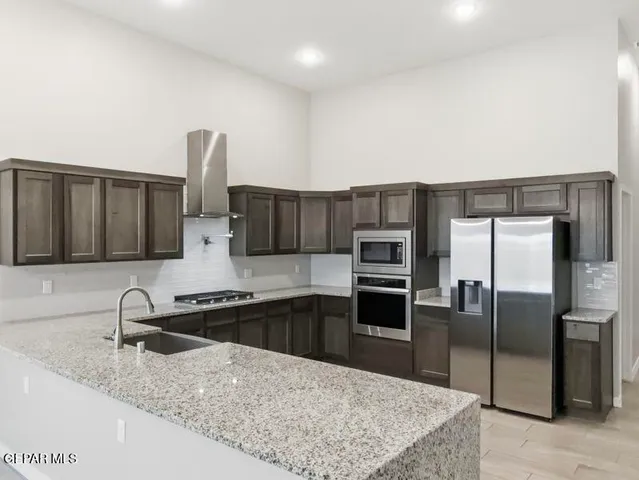 a kitchen with stainless steel appliances granite countertop a sink refrigerator and microwave