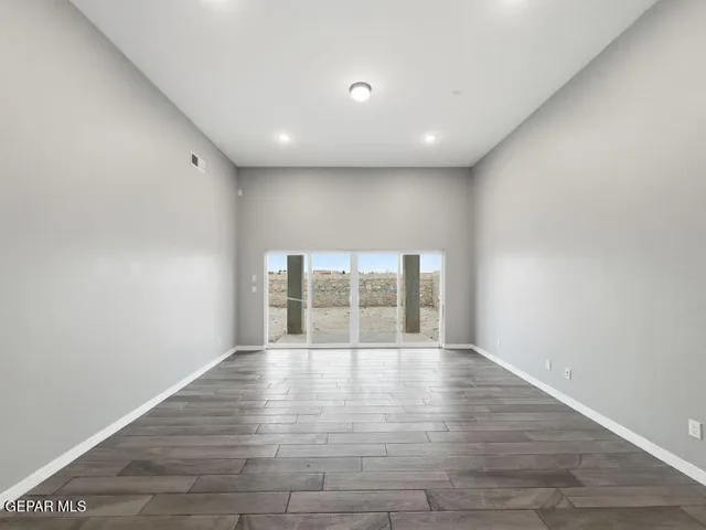 a view of an empty room with a window and wooden floor