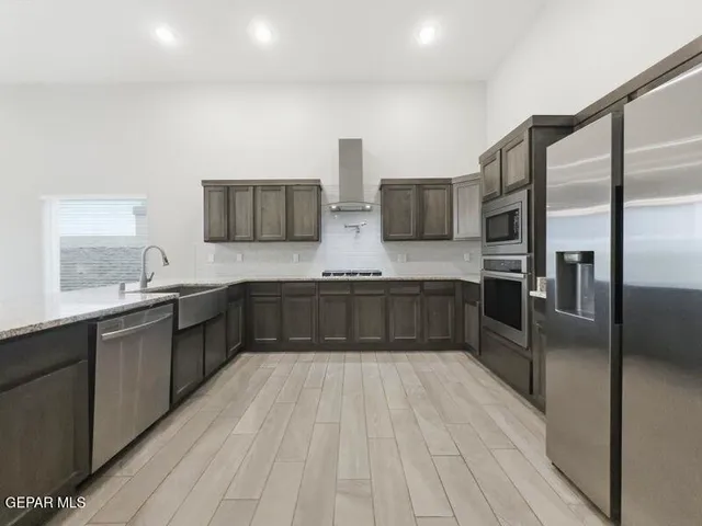 a large kitchen with stainless steel appliances a large counter top and a wooden floors