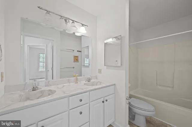 a bathroom with a granite countertop sink a toilet and a large mirror
