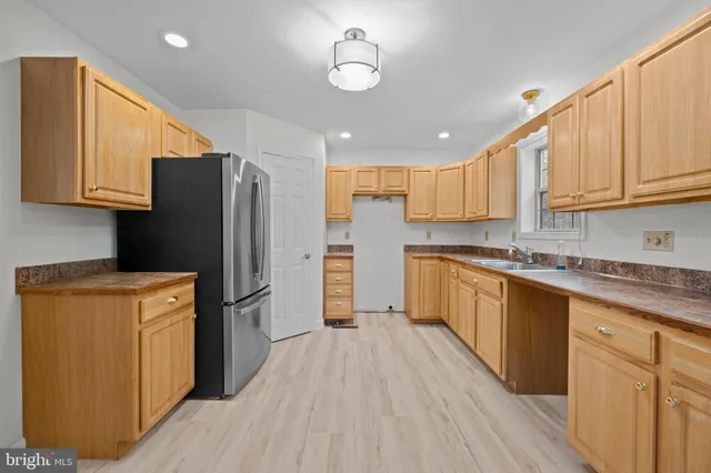 a kitchen with stainless steel appliances granite countertop a refrigerator a sink dishwasher a stove and white cabinets with wooden floor