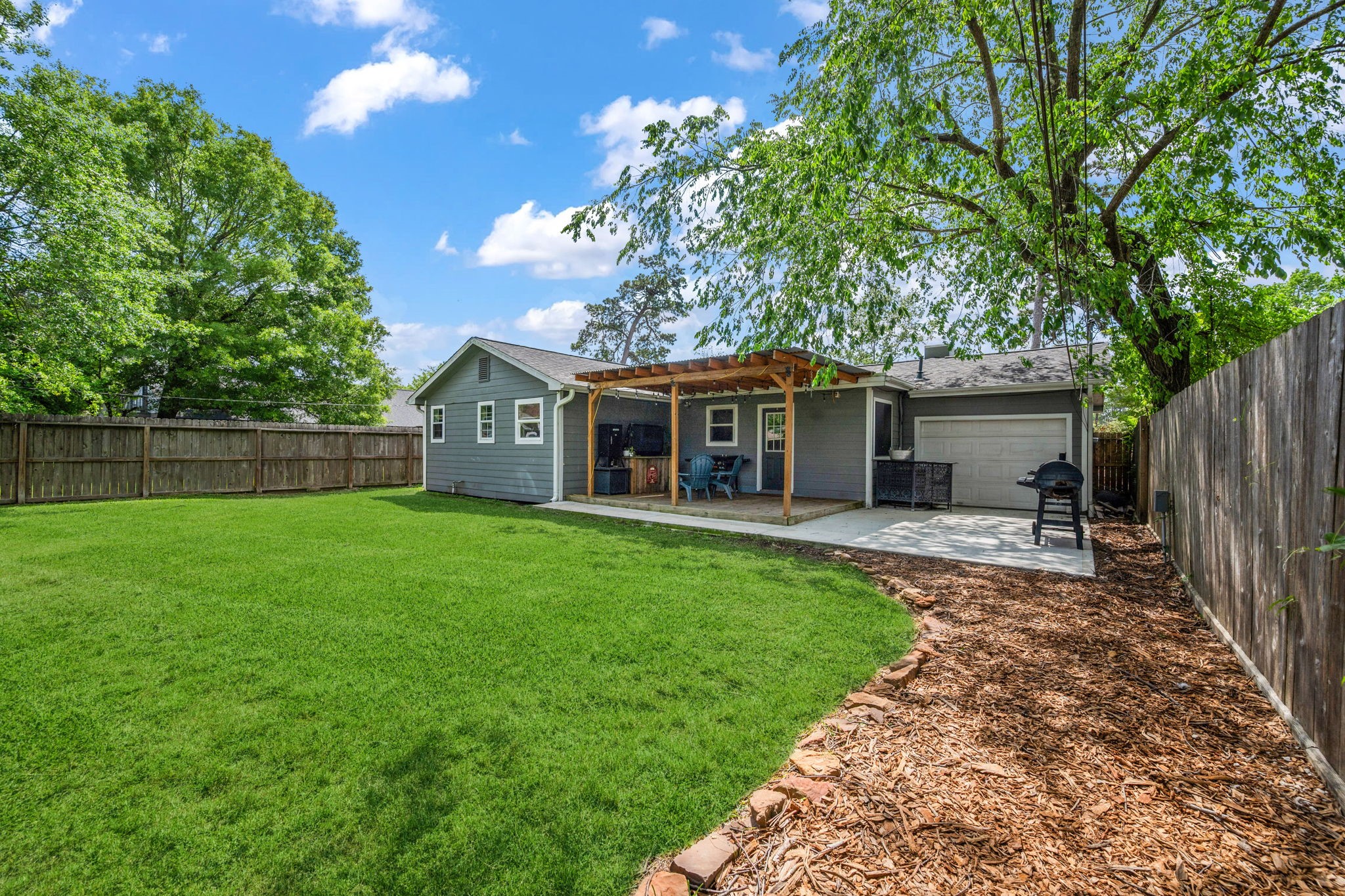 431 Corydon Drive Houston, TX 77336 - Photo 24 of 26 Expansive backyard featuring a lush, well-maintained lawn framed by mature trees. The covered patio extends the living space outdoors, creating a comfortable setting for relaxing or entertaining, with a convenient hot tub connection already in place.