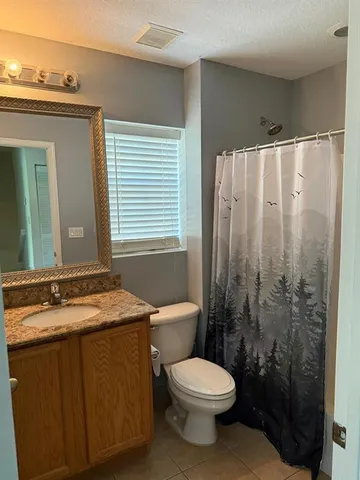 a bathroom with a granite countertop sink toilet and shower