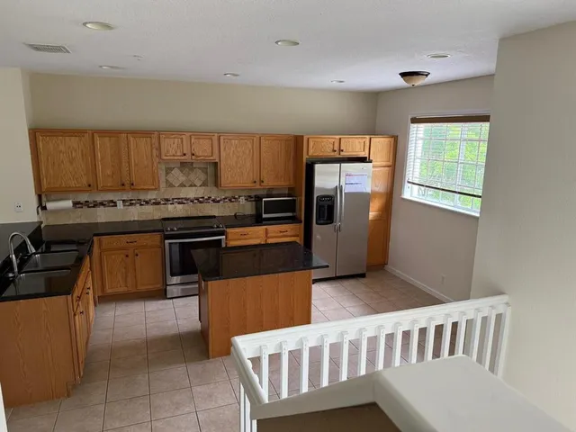 a kitchen with stainless steel appliances granite countertop a stove a sink a refrigerator and island