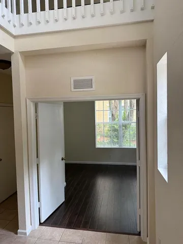 a view of an empty room with wooden floor and a window