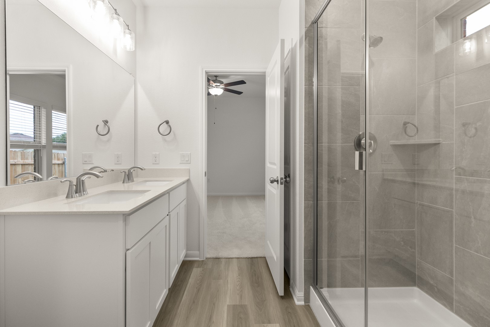 18605 Emu Lane Manor, TX 78653 - Photo 22 of 27 Bathroom featuring a double vanity with white cabinetry and a large mirror, alongside a shower with a glass enclosure and tiled walls