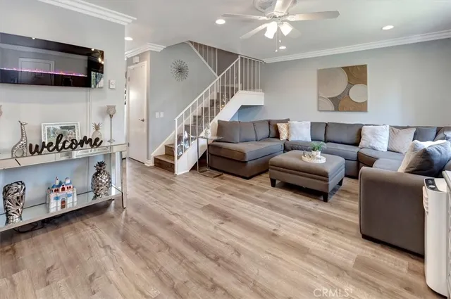 a living room with furniture kitchen view and a wooden floor