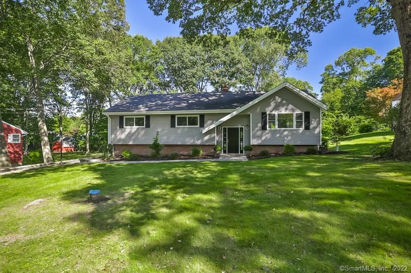 a view of a house with a big yard potted plants and large tree