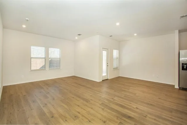 a view of an empty room with wooden floor and window