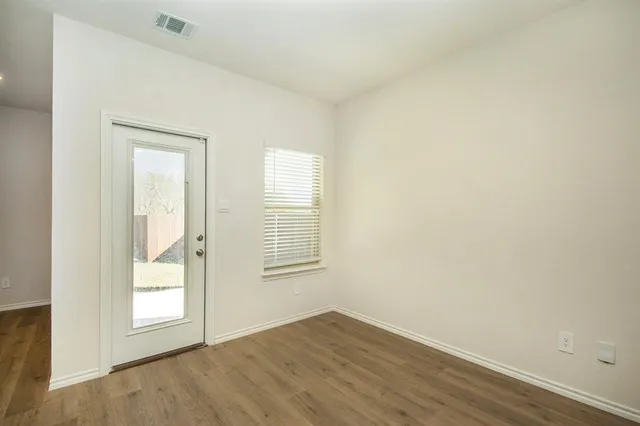 an empty room with wooden floor and windows