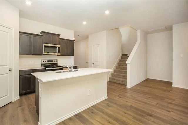 a kitchen with kitchen island a sink a stove a microwave and wooden floors