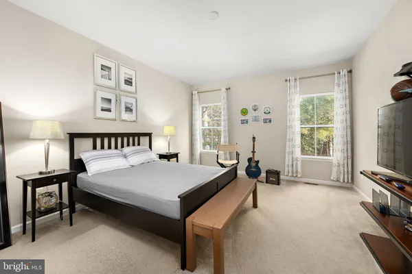 a bedroom with a bed a tv and next to a window