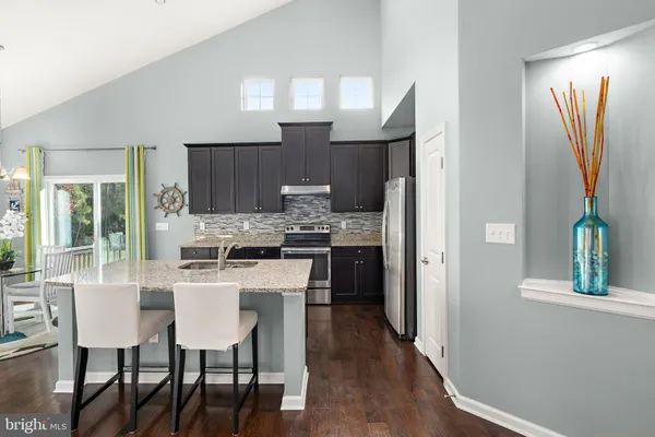 a kitchen with stainless steel appliances a dining table chairs refrigerator and cabinets