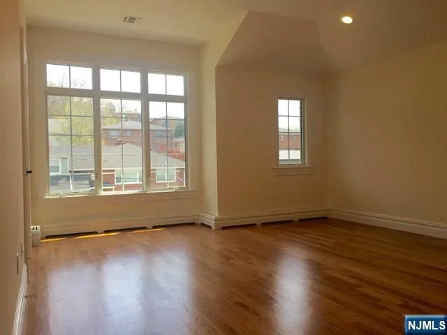 a view of an empty room with glass window and hardwood floor