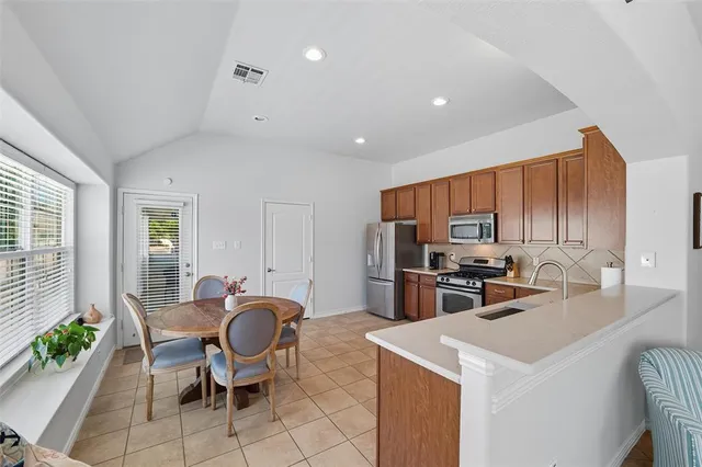 a kitchen with a dining table chairs and refrigerator
