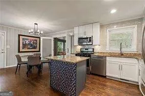 a kitchen with kitchen island granite countertop a sink counter top space appliances and cabinets