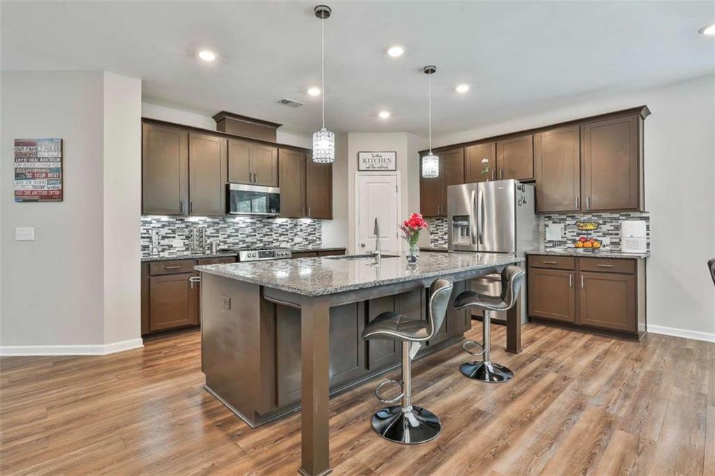 8 Unbridled Way Newnan, GA 30263 - Photo 17 of 49 a kitchen with kitchen island granite countertop a sink cabinets and wooden floor