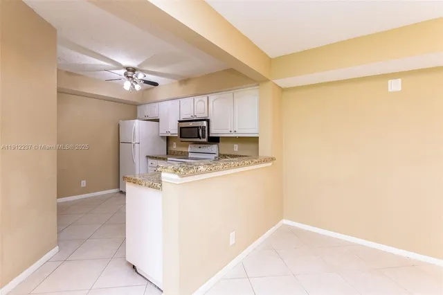 a kitchen with kitchen island a counter top space appliances and a ceiling fan