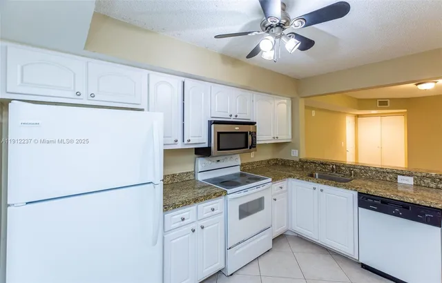 a kitchen with granite countertop cabinets appliances and a counter space