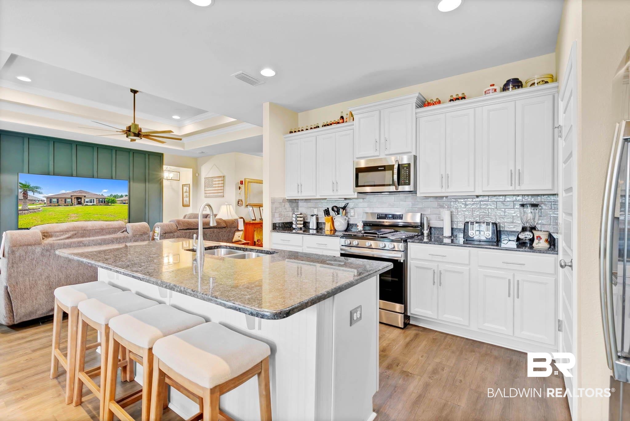 2049 Bourbon Street Foley, AL 36535 - Photo 55 of 56 Kitchen featuring appliances with stainless steel finishes, open floor plan, light wood-type flooring, backsplash, and a breakfast bar area