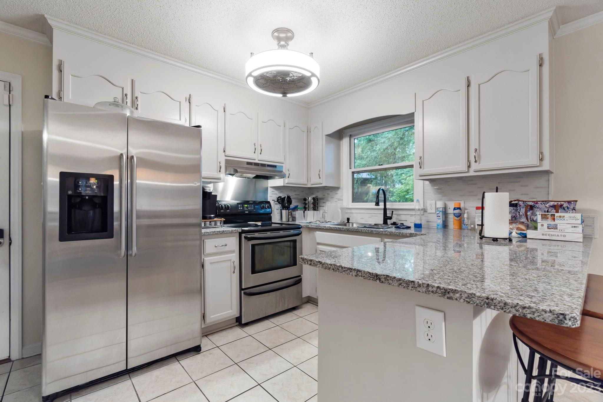 1007 Charcoal Ridge Court Matthews, NC 28105 - Photo 5 of 16 a kitchen with granite countertop stainless steel appliances a refrigerator sink and microwave
