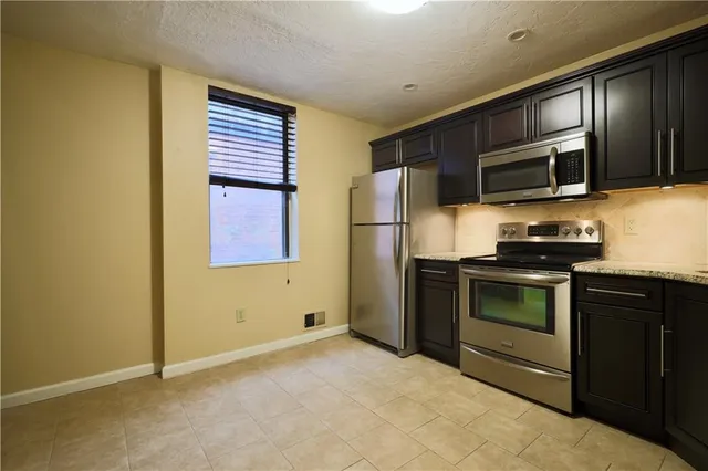 a kitchen with stainless steel appliances granite countertop a refrigerator and a stove top oven