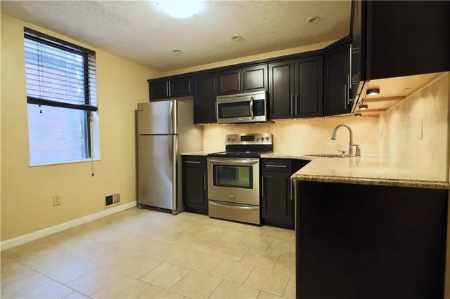 a kitchen with stainless steel appliances granite countertop a refrigerator stove top oven a sink and dishwasher