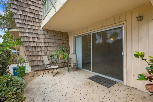 a patio with table and chairs and potted plants
