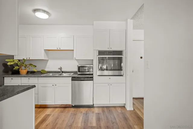 a kitchen with stainless steel appliances a stove a sink and white cabinets