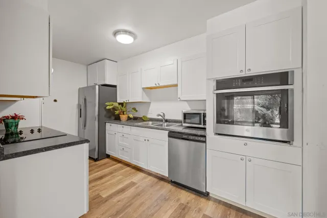 a kitchen with granite countertop white cabinets and stainless steel appliances