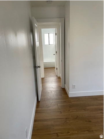 230 North 2nd Street Tooele, UT 84074 - Photo 16 of 18 Hallway with wood-finish flooring, leading to a bathroom featuring a white tub and tiled surround