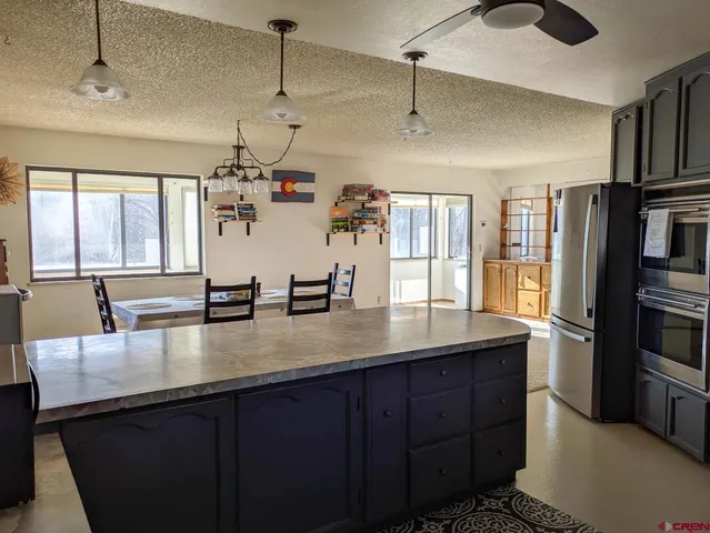 a kitchen with stainless steel appliances granite countertop a sink a counter space and a refrigerator