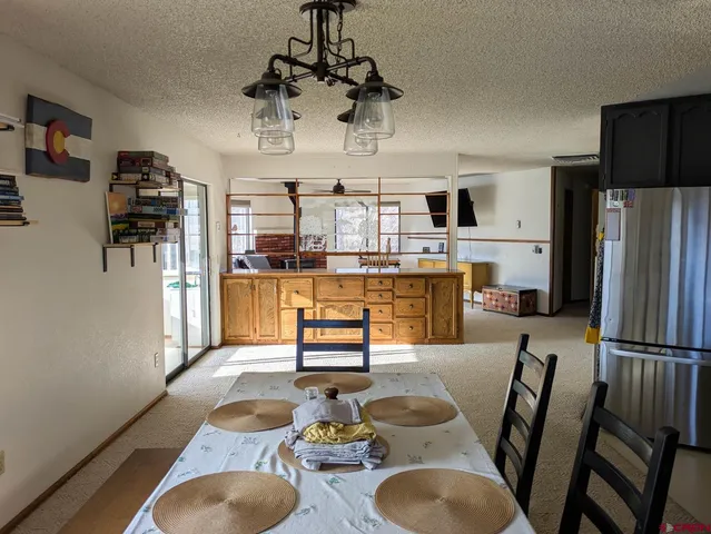 a kitchen with stainless steel appliances granite countertop a sink dishwasher a refrigerator and a dining table with wooden floor