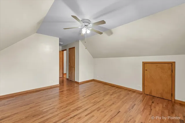 an empty room with wooden floor chandelier fan and windows