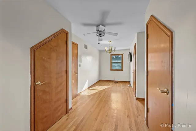 a view of hallway with wooden floor and chandelier