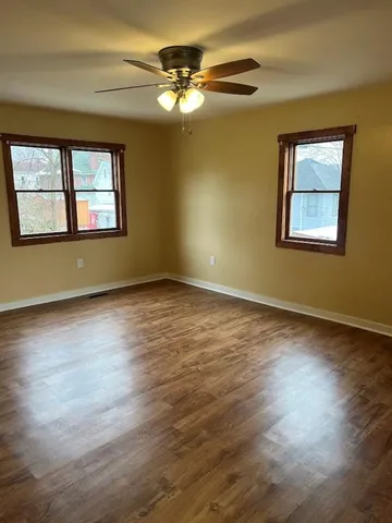 a view of an empty room with wooden floor and a window