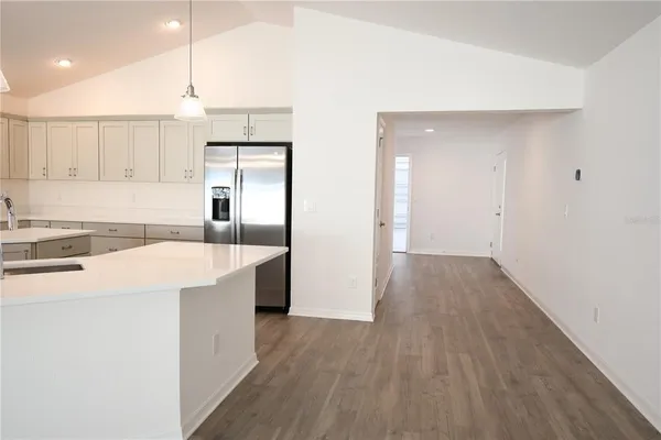 an open kitchen with a sink a refrigerator and wooden cabinets