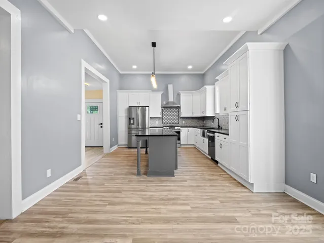 a large kitchen with stainless steel appliances kitchen island a stove a refrigerator a sink dishwasher and a oven with wooden floor