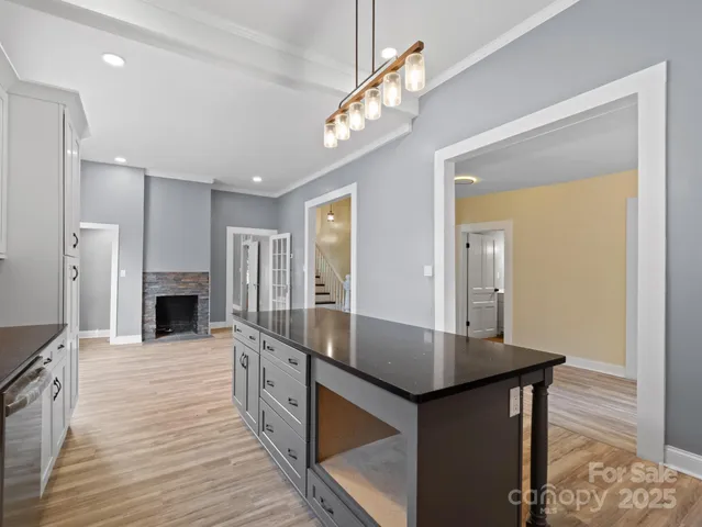 a view of a hallway with wooden floor and a kitchen view