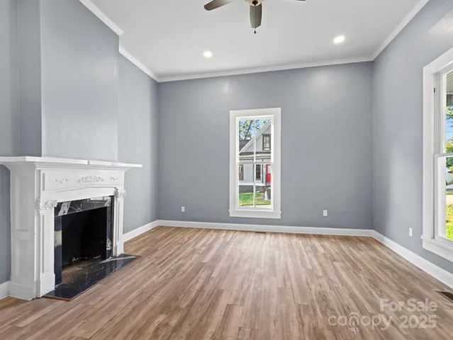an empty room with wooden floor fireplace and windows